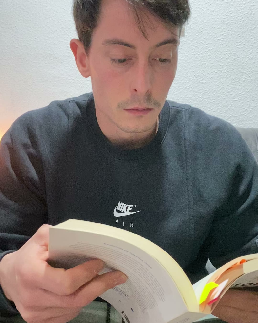 Alejandro Arias leyendo un libro en el sofá de casa
